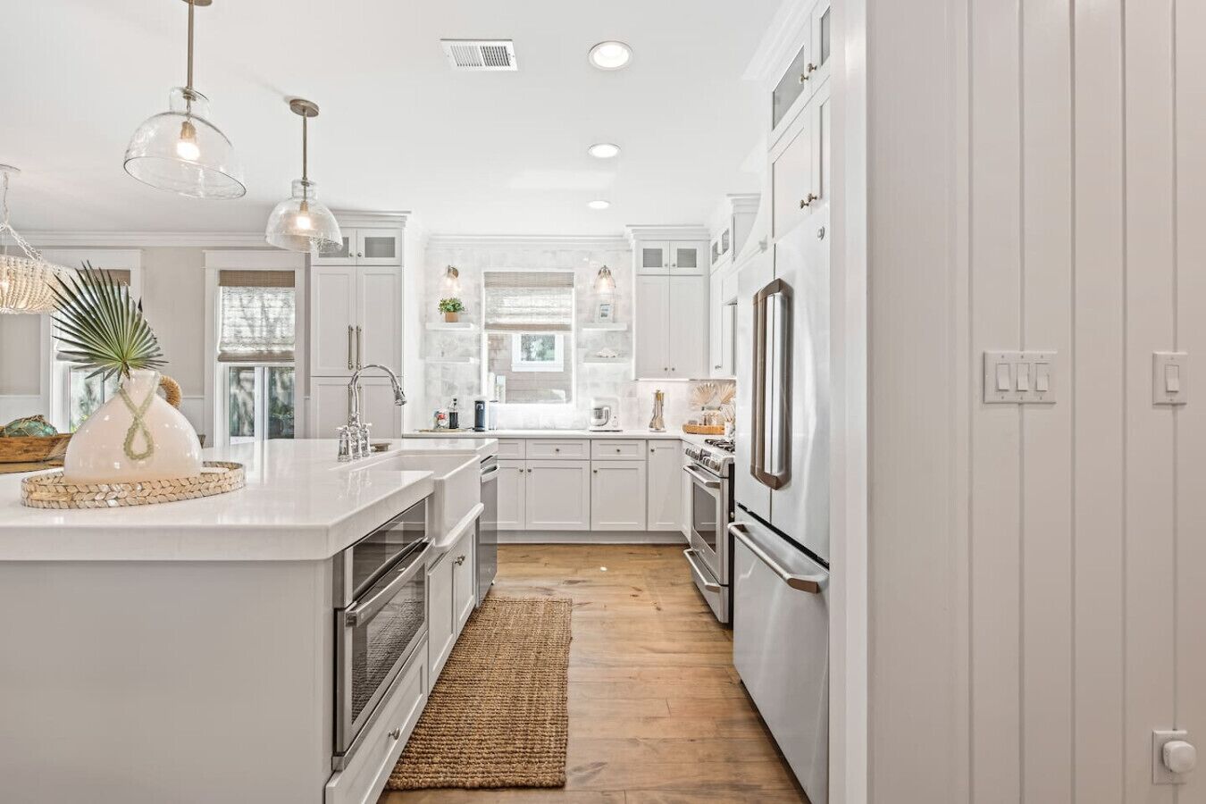 A modern kitchen with white cabinets, stainless steel appliances, and pendant lighting.