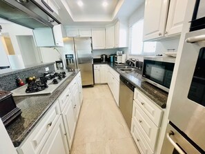 A modern kitchen with white cabinets, stainless steel appliances, a granite countertop, and a dishwasher. - Tranquil 2-bedroom townhome near Hermosa Beach and Redondo Pier. Pet friendly! (Redondo Beach)