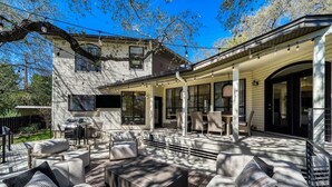A covered patio with outdoor furniture, a grill, and a large window overlooking the yard. - LuxuryLake Austin Retreat: Game Room + Fire Pit, Minutes to Downtown (Austin)