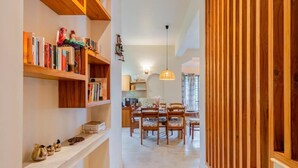 Un pasillo con estanterías de madera, un comedor con sillas y una cocina al fondo.