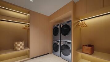 Un lavadero con cuatro lavadoras apiladas, estanterías de madera y perchas para ropa.