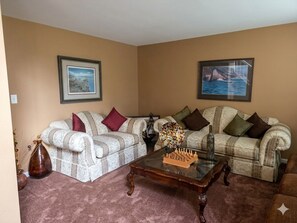 Ein Wohnzimmer mit zwei gemusterten Sofas, einem Couchtisch und zwei gerahmten Bildern an den Wänden.