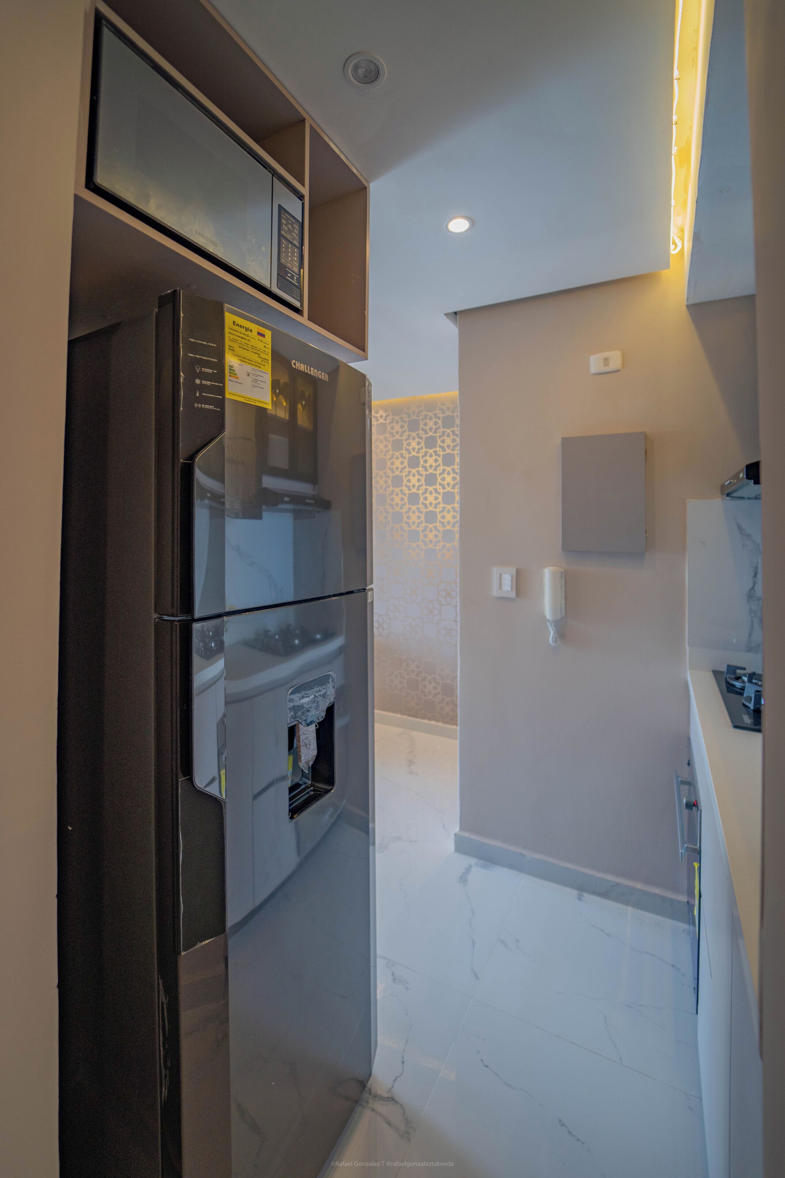 A compact kitchen with a refrigerator, a microwave, and a built-in oven.