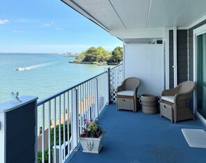 A balcony with wicker furniture, a potted plant, and a view of the water. - Ocean City MD Harbour Island Bay View Condo (Ocean City)