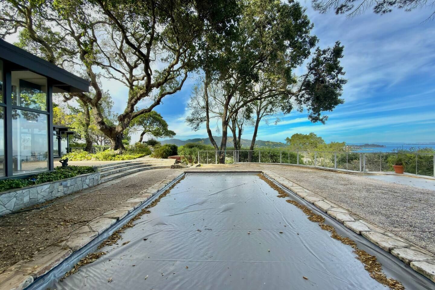 Une terrasse sur le toit offrant une vue sur la mer, entourée d’arbres et bordée d’un bâtiment moderne.