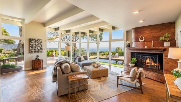 Amplia sala de estar con chimenea, ventanas grandes y vista al exterior.