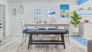 Un coin repas avec une table en bois, des chaises rembourrées bleues, un lustre et une plante en pot.