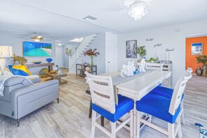 Una sala moderna con comedor, escalera y un cuadro de un paisaje urbano.