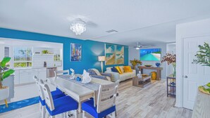 Un salon moderne comprenant un coin repas, une cuisine et une vue sur l’océan.
