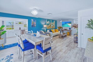 Una sala de estar moderna con comedor, cocina y vista al océano.