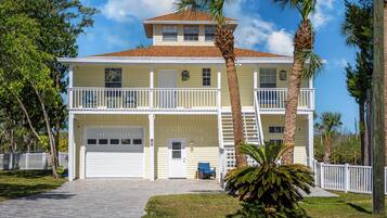 A two-story building with a front garage, a balcony on the upper floor, and a small porch area.