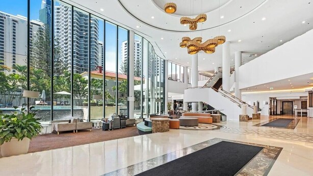A spacious lobby with a central staircase, seating areas, and large windows offering views of the surrounding buildings. - Skyline Hideaway Studio (Gold Coast)