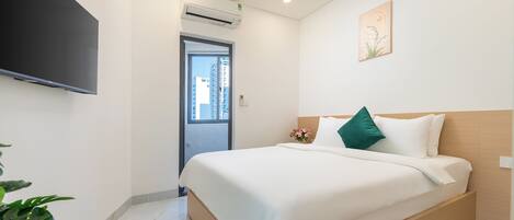 Una habitación de hotel con una cama, un televisor, una ventana y una planta.