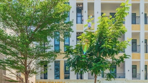A multi-story building with a ground-floor boutique hotel, balconies, and a tree in front. - LINH KHANG 1 Hotel & Apartment Da Nang (Da Nang)