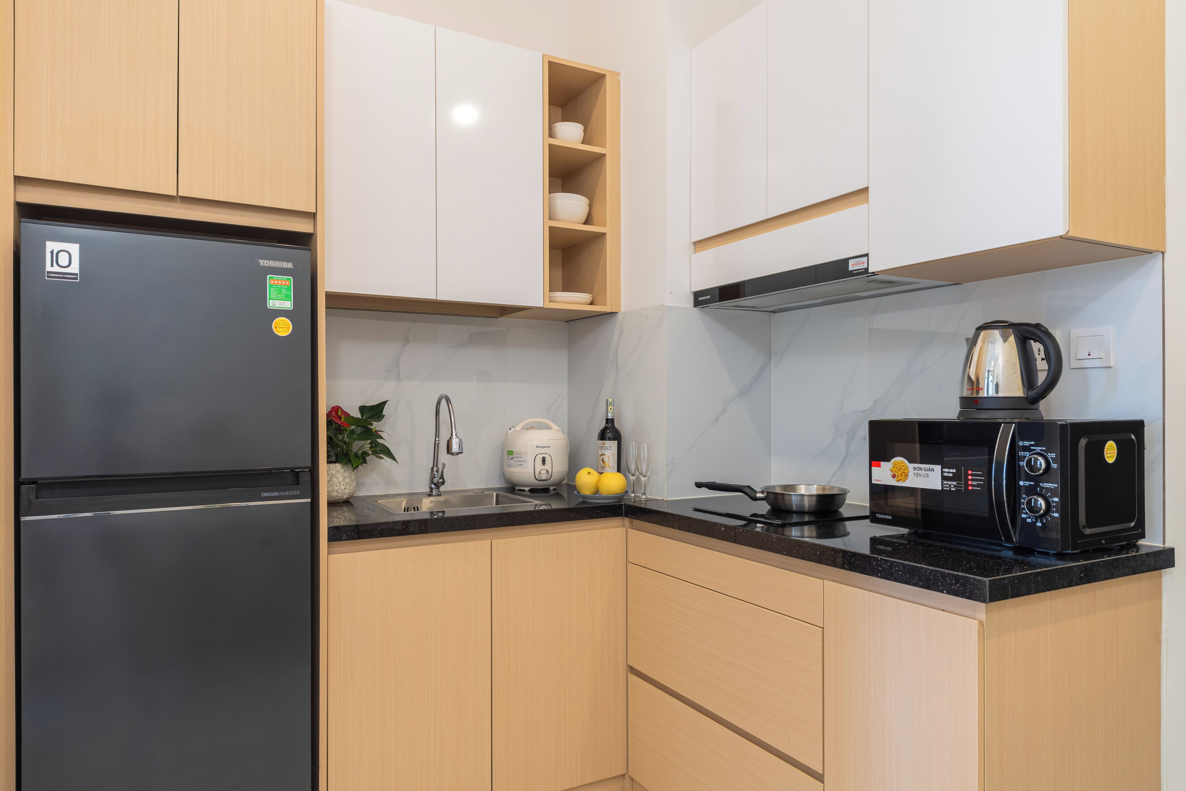A modern kitchen with a refrigerator, microwave, toaster, and sink.