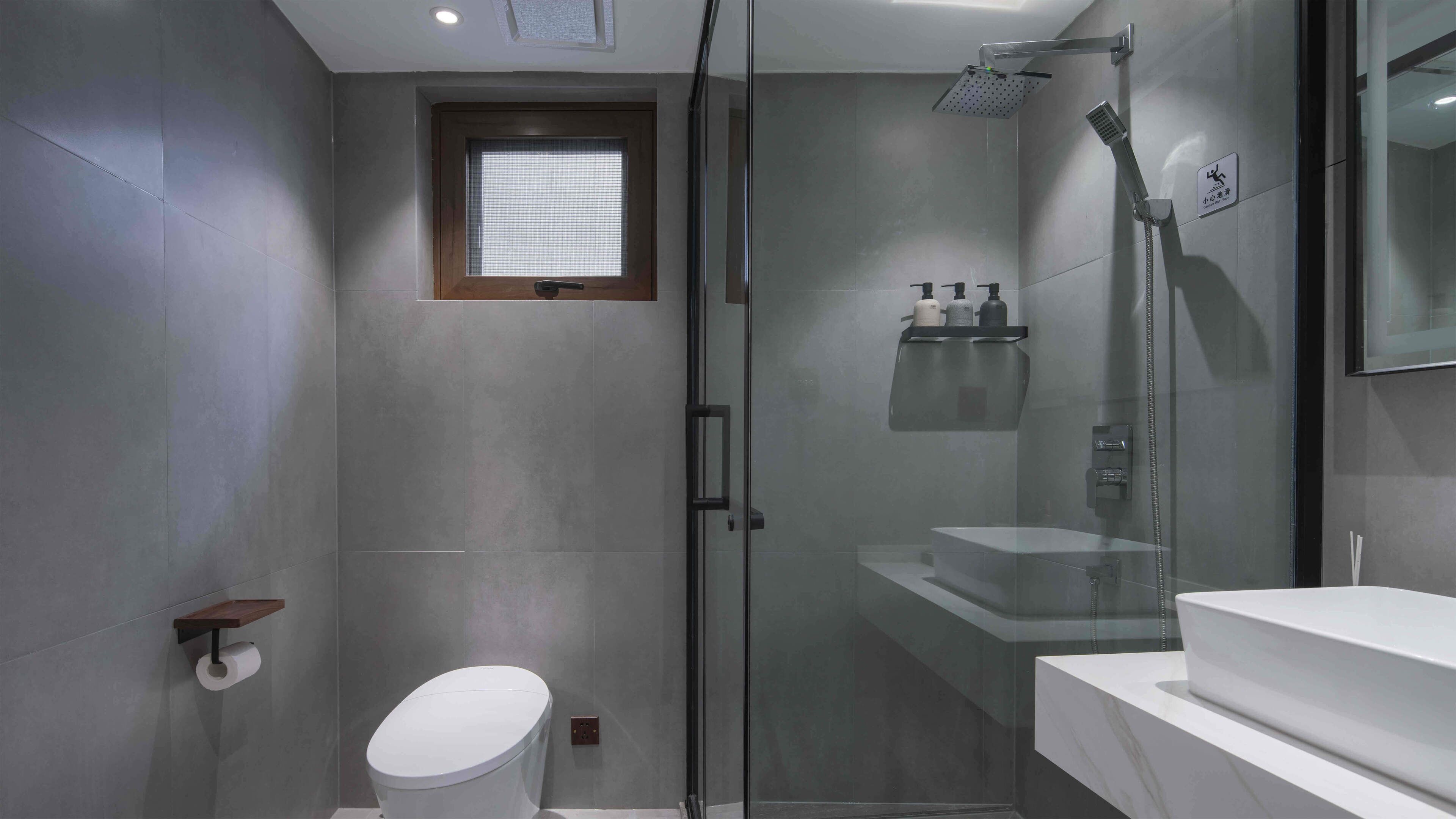Un bagno moderno con doccia vetro, WC e lavandino con specchio.