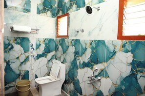A bathroom with a toilet, a shower, and a marble-patterned wall. - Senthur Stay Homes (Tiruchirappalli)