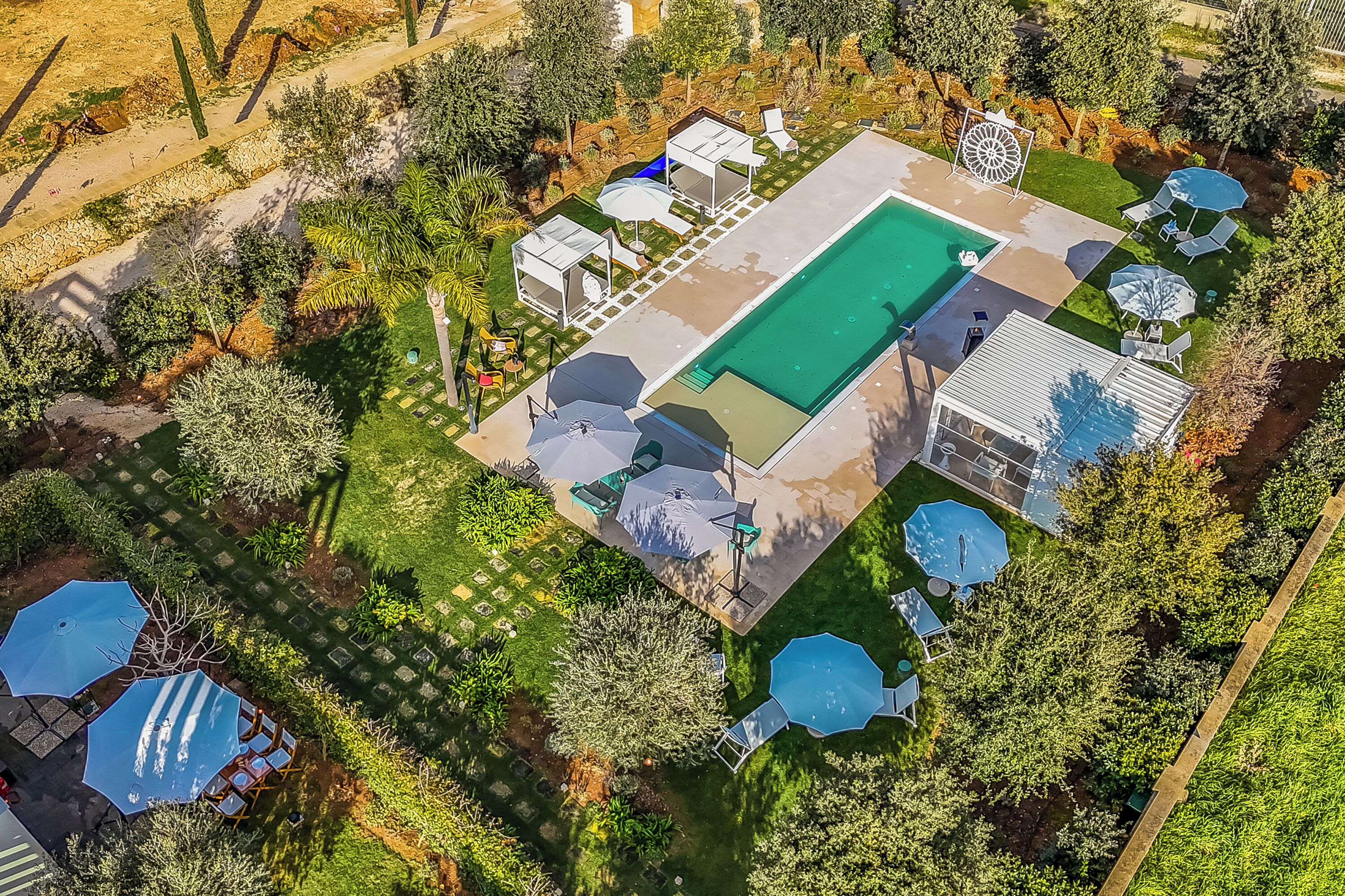 Ein Luftbild eines Wohnhauses mit Swimmingpool, Liegestühlen und einer überdachten Terrasse.