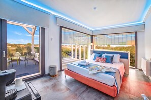 Un dormitorio moderno con una cama grande, una mesita y una silla.