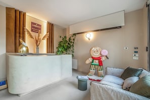 A reception area with a wooden reception desk, a large gingerbread man decoration, a potted plant, and a modern couch. - Alternative Room 4 Relax & SPA, Scorrano, Italy (Scorrano)
