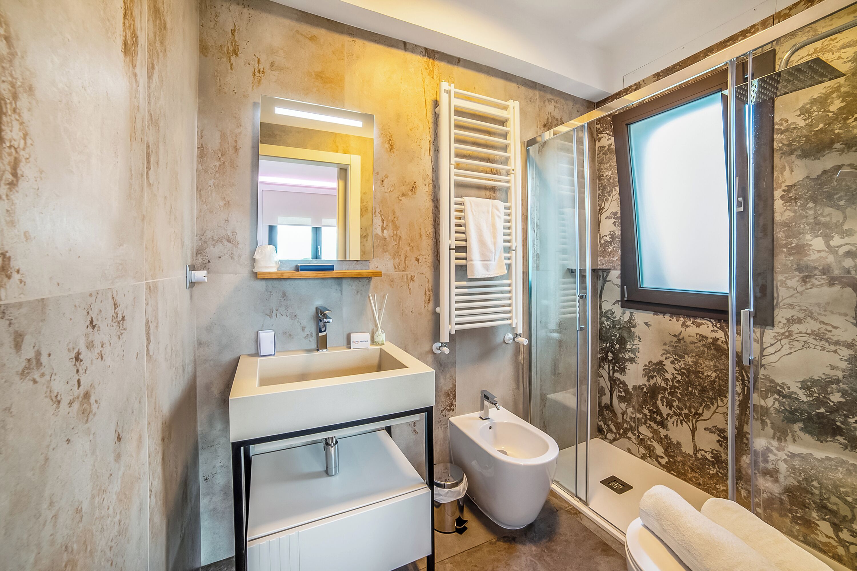 Un bagno moderno con un lavandino grande, uno specchio, un bidet e un box doccia in vetro.