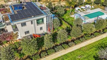 Ein modernes Haus mit Solaranlage, Swimmingpool und einem gepflegten Garten.