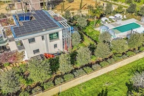 A modern house with solar panels, a swimming pool, and a well-maintained garden.