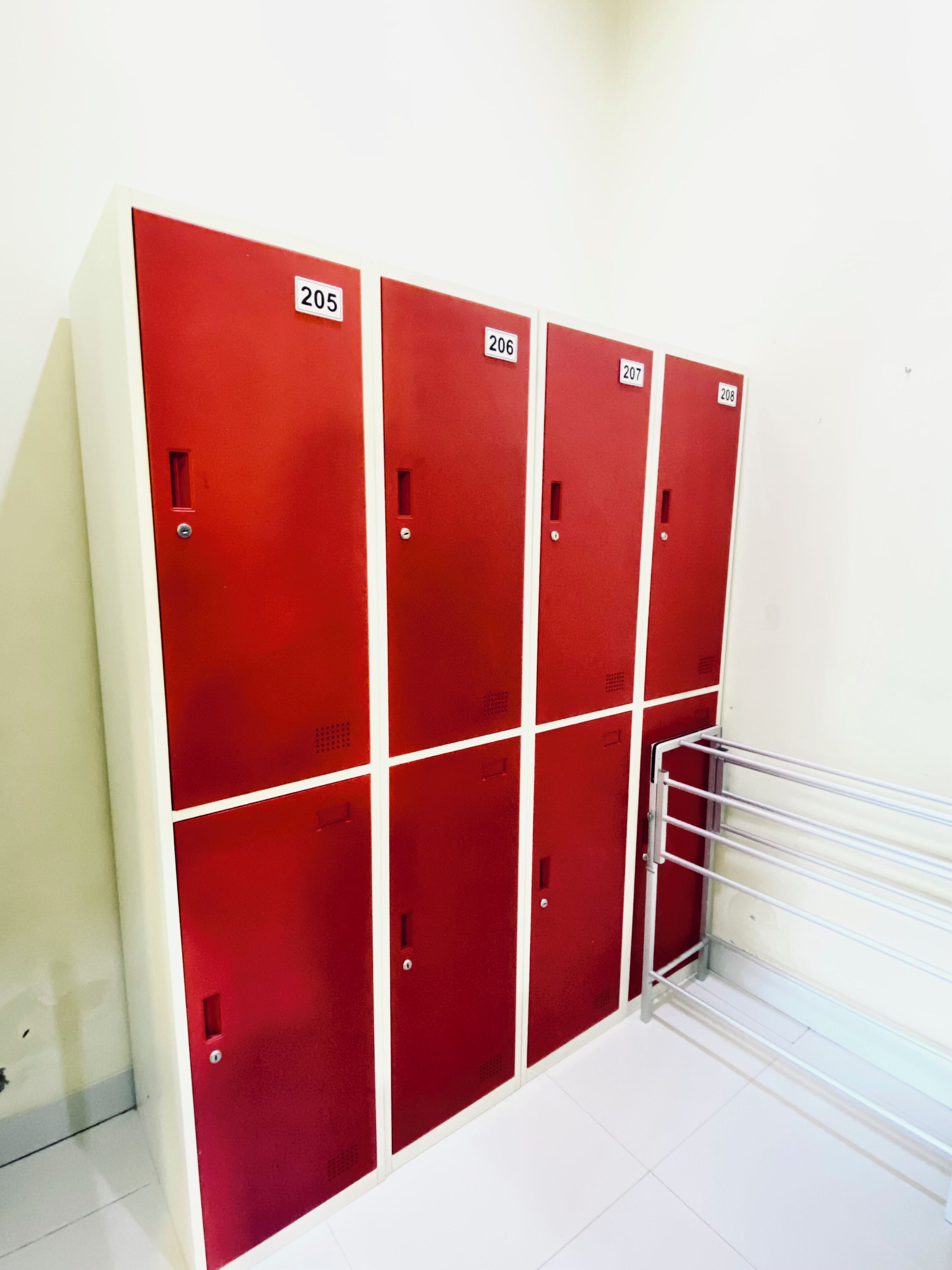 A row of red lockers numbered 205 to 208, with a metal rack on the right.