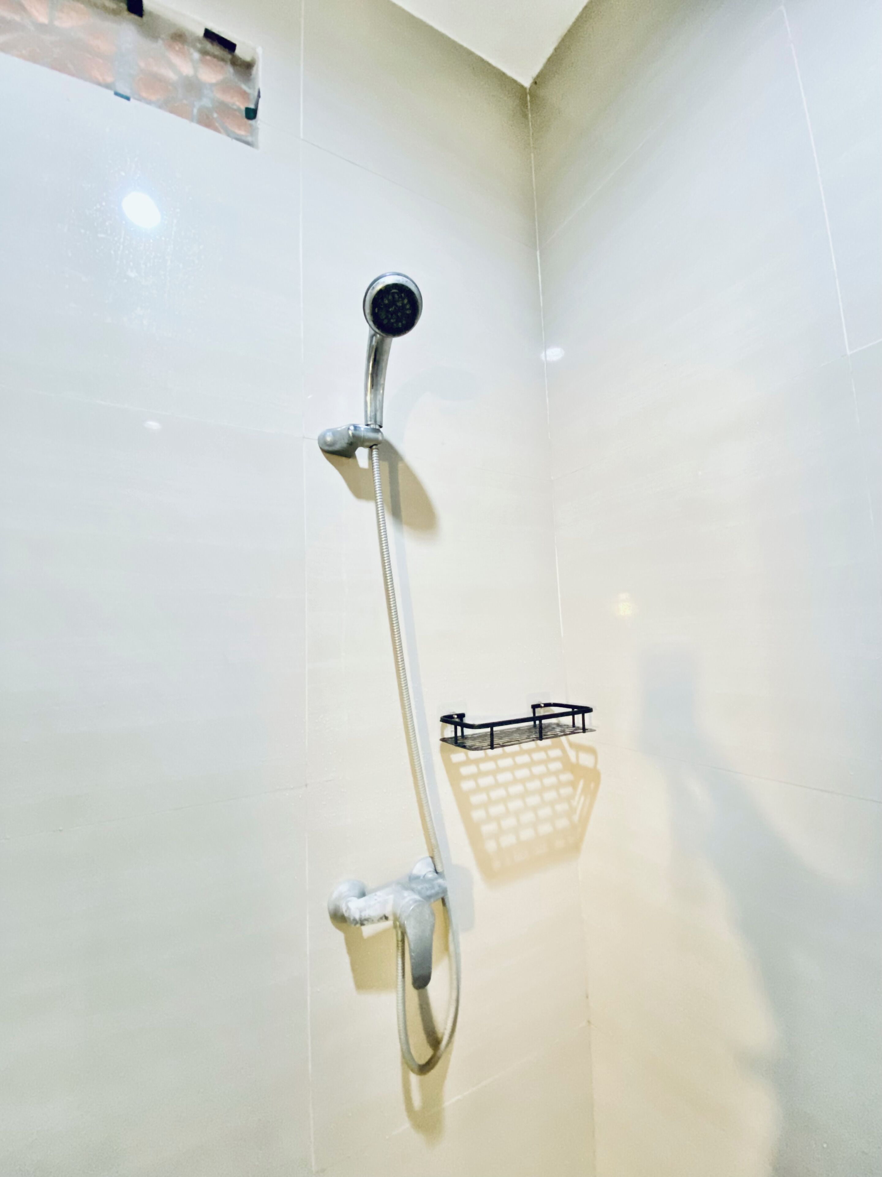 A shower with a handheld showerhead, a handheld shower attachment, and a wall-mounted shower head.