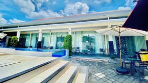 A hotel with a swimming pool, outdoor seating, and a covered patio area. - V Canggu Dormitory (Tibubeneng)