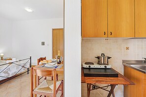 A kitchen with wooden cabinets, a portable gas stove, and a dining table with chairs.