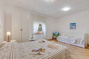 Un dormitorio con una cama grande, televisión y ventana con cortinas.