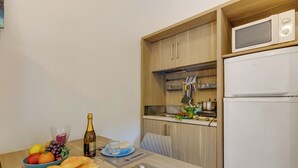 Eine kleine Küche mit einer Mikrowelle, einem Kühlschrank und Holzschränken.