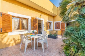 Eine Terrasse mit Tisch, Stühlen und einem kleinen Gartenbereich mit Pflanzen.