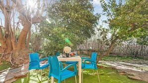 An outdoor dining area with a table and chairs, surrounded by trees and greenery. - Residence Argentiera Studio 10 for four, Miniera dell’Argentiera, Italy (Miniera dell’Argentiera)