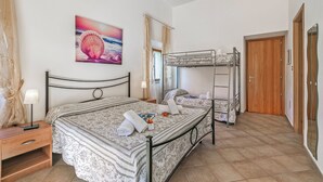 A bedroom with a bunk bed, a bedside table with a lamp, a painting on the wall, and a wooden door. - Residence Argentiera Studio 10 for four, Miniera dell’Argentiera, Italy (Miniera dell’Argentiera)