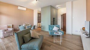 A modern living room with a sofa, chairs, a small table, and a TV. - Lake View Escape Apartment with Pool, & Terrace in Stresa, Stresa, Italy (Stresa)