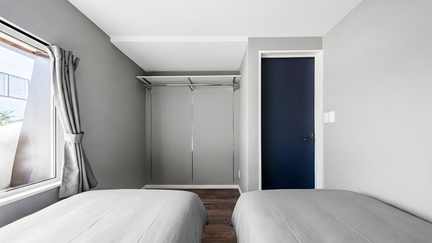 Une chambre avec deux lits, une fenêtre avec des rideaux, une armoire et une porte.