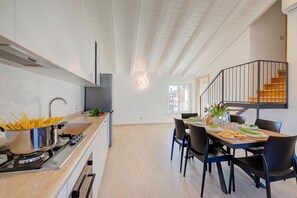 Et moderne køkken med komfur, vask og et spiseområde med stole og bord.