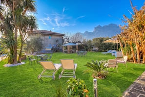 A well-maintained outdoor area with a lawn, seating arrangements, and a building in the background. - Agritur Laura- Sogno zen 6 with Shared Garden, Torbole sul Garda, Italy (Torbole sul Garda)