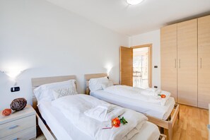 A hotel room with two single beds, a wooden wardrobe, a bedside table with a lamp, and a wall-mounted charging station. - Agritur Laura- Sogno zen 6 with Shared Garden, Torbole sul Garda, Italy (Torbole sul Garda)