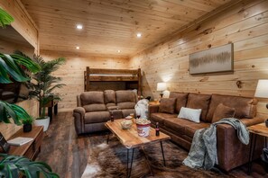Ein gemütliches Blockhaus-Interieur mit Holzboden, Ledersofas, einem Holztisch und einer großen Pflanze.