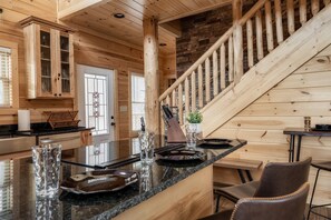 Un intérieur en bois comprenant un îlot de cuisine, un escalier et un coin repas.