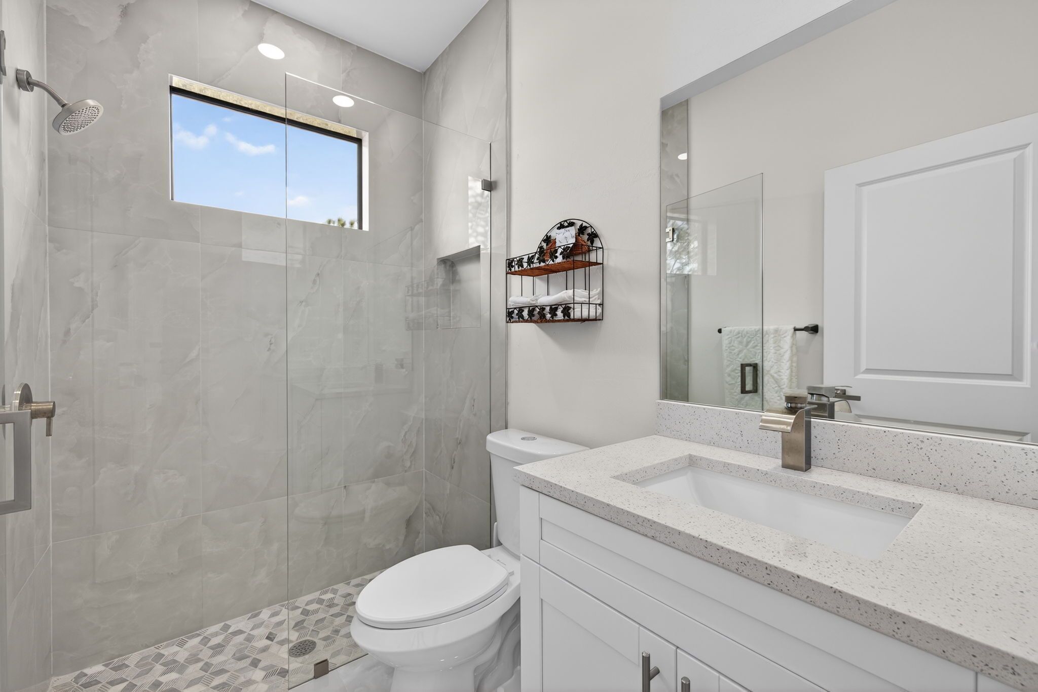 A modern bathroom with a shower, toilet, and a large mirror.