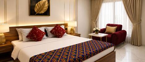 Una habitación de hotel con una cama grande, un sillón rojo, una mesita con flores y una obra de arte colgada en la pared.
