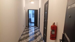 A hallway with a marble floor, a fire extinguisher, and a door on the right. - Casa de royal guest house (Kasoa)