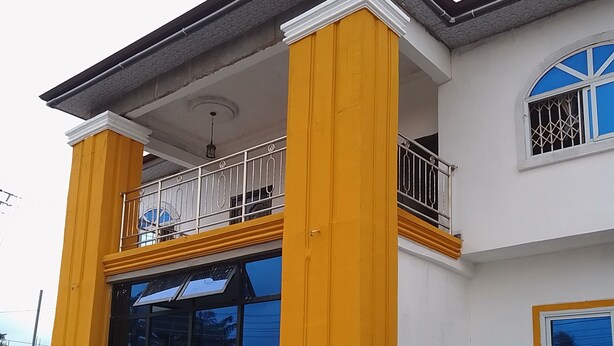 A two-story building with a balcony, large windows, and a staircase. - Casa de royal guest house (Kasoa)