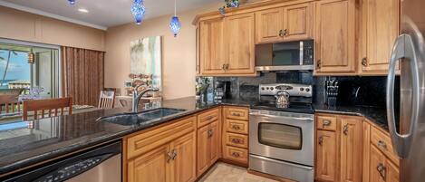 A modern kitchen with wooden cabinets, stainless steel appliances, and a black countertop.