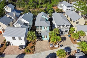 A residential area with multiple houses, some with attached garages, and a central house with a prominent blue roof. - Sage & Sand: Golf Cart, Bikes & Pickleball (Santa Rosa Beach)