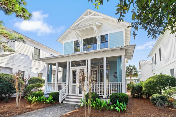 A two-story house with a porch, surrounded by well-maintained landscaping and neighboring houses. - Sage & Sand: Golf Cart, Bikes & Pickleball (Santa Rosa Beach)